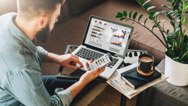 young man online marketing working on laptop with smartphone in hand