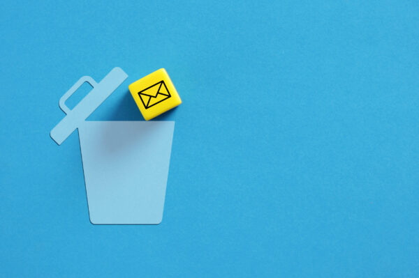 Yellow cube with email symbol falling into blue trash can stock photo