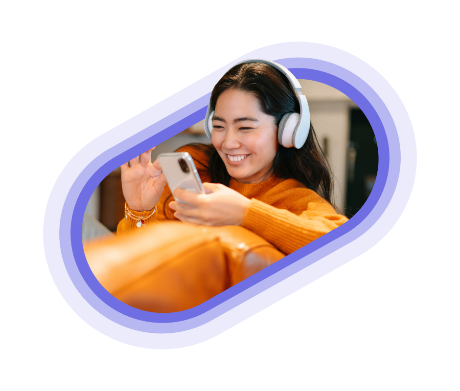 A person in an orange jumper using their headphones and mobile