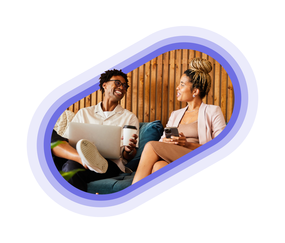 A person on a laptop smiling at a person holding their phone
