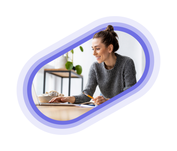 A person with a pen and a laptop making notes