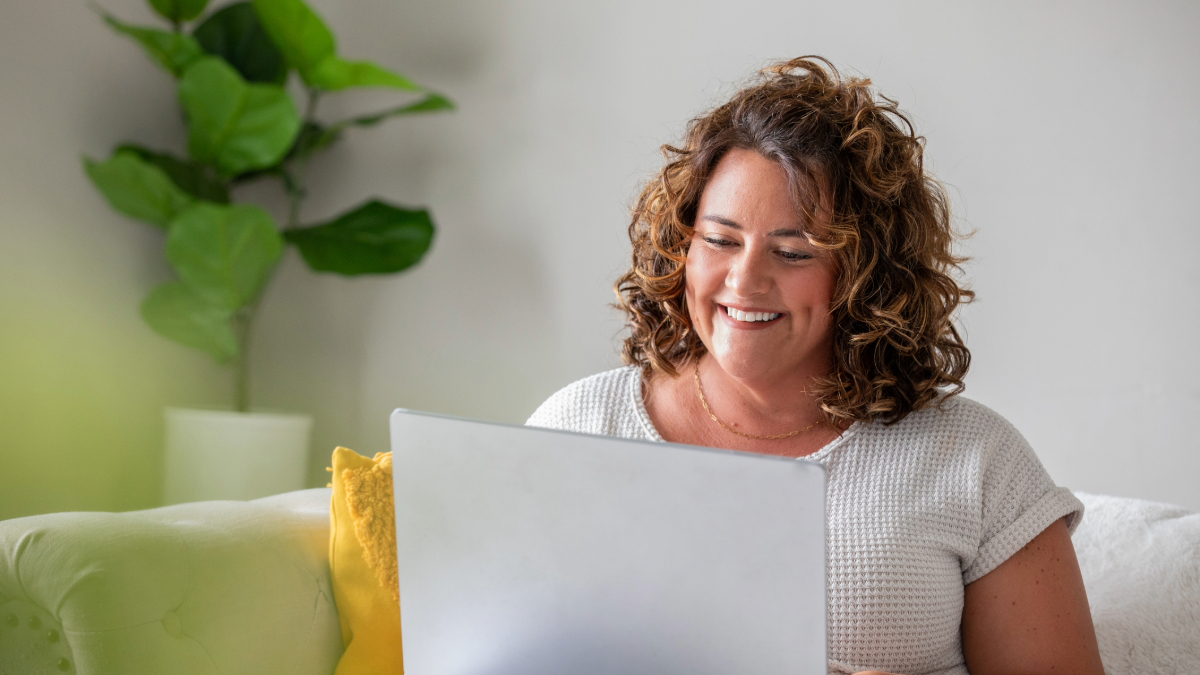 Happy loyal customer with curly hair looking at a laptop.