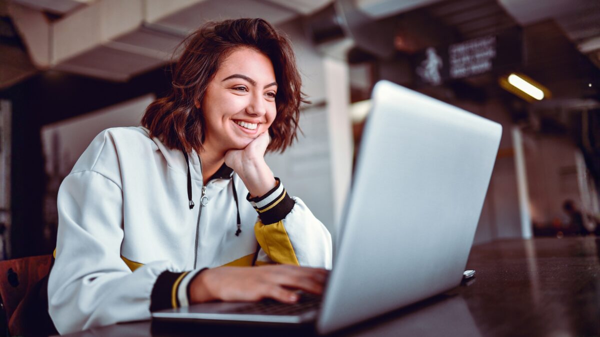 Happy woman smiling at laptop writing for email