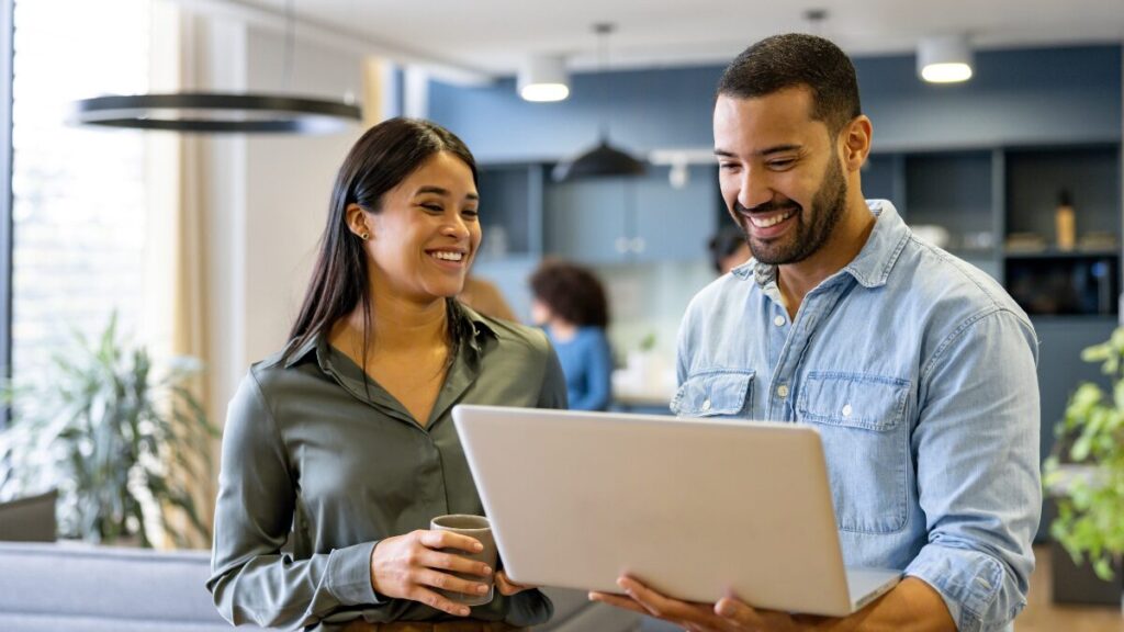 Woman and man smiling at their laptop