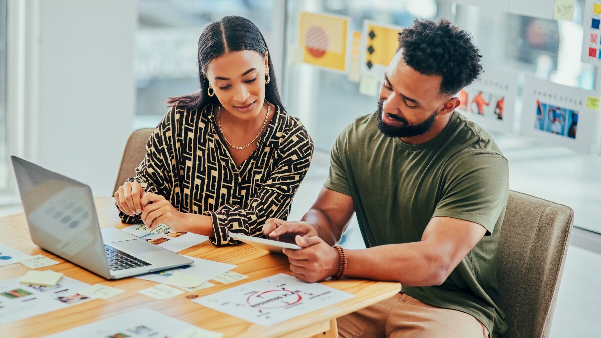Shot of two young marketers working on a laptop and digital tablet in an office