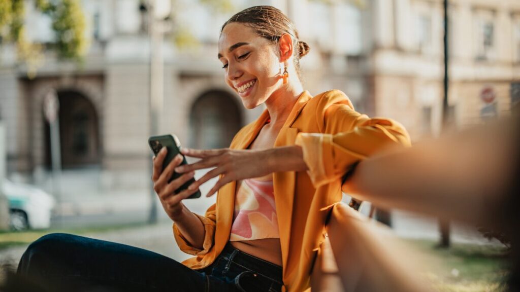 Consumer sitting on a bench smiling because she has received relevant marketing