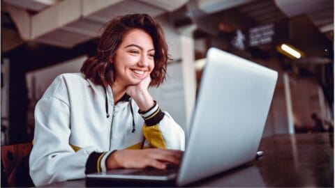 Happy woman smiling at laptop writing for email