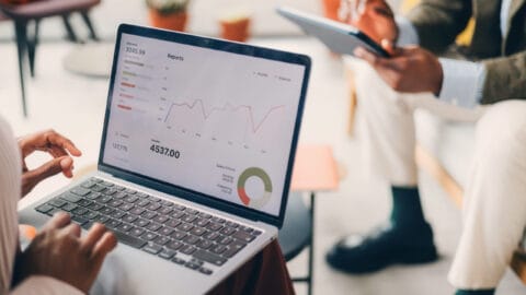 Business Team Analyzing Financial Data on Laptop with Digital Reports